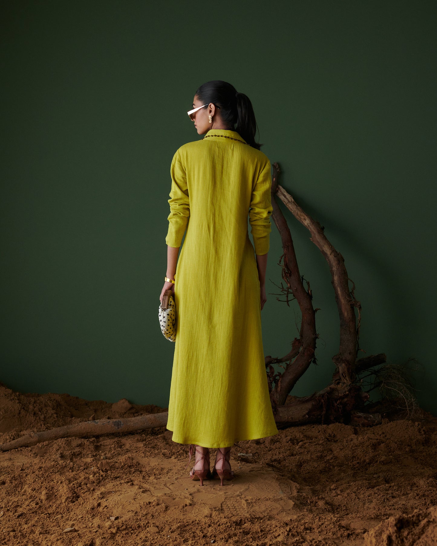 Back view of model wearing Aam Panna mango yellow midi dress by Naarangi, highlighting textured fabric and flowing design.