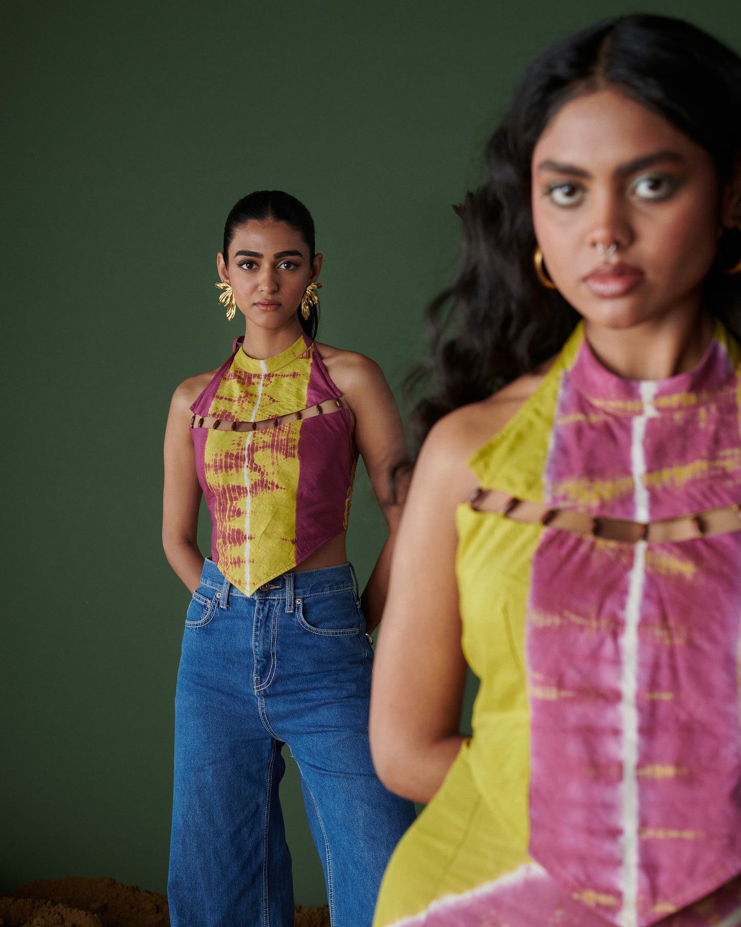 Model wearing Khatta Jaljeera Top in handcrafted mustard yellow and magenta pink tie-dye halter-neck style, paired with blue denim, from Naarangi’s Chaska collection.