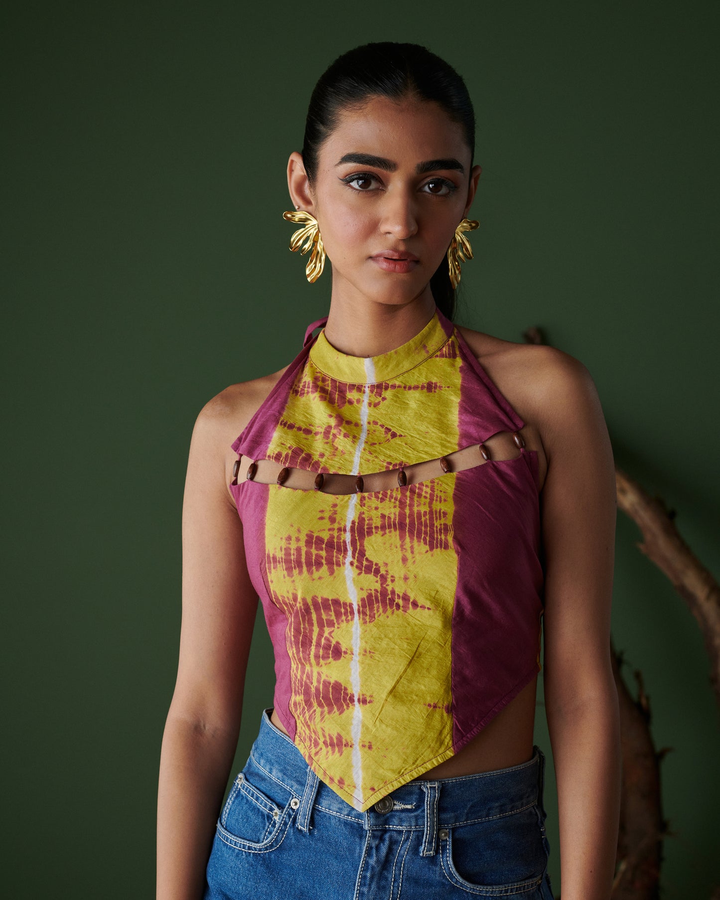 Close-up front view of Meetha Jaljeera Top in wine and deep yellow by Naarangi, a vibrant women’s halter-neck top with cut-out accents, hand-dyed using traditional techniques, styled with blue denim jeans, blending ethnic craftsmanship with modern boho-chic fashion in India.