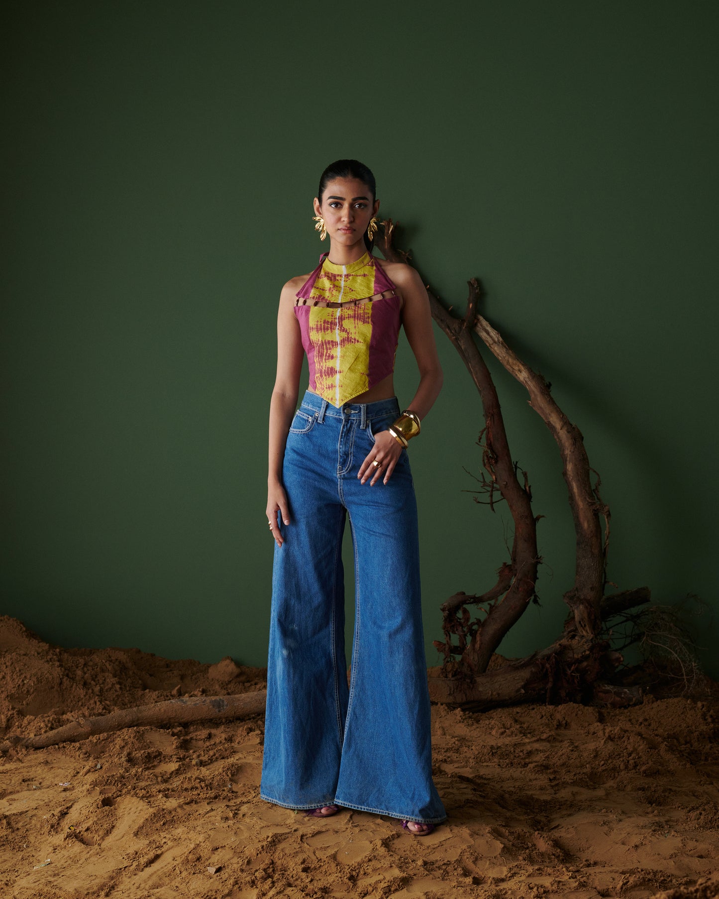 Full-body view of Meetha Jaljeera Top in wine and deep yellow by Naarangi, a vibrant women’s halter-neck top with cut-out accents, hand-dyed using traditional techniques, paired with wide-leg blue denim jeans, blending ethnic craftsmanship with modern boho-chic fashion in India.