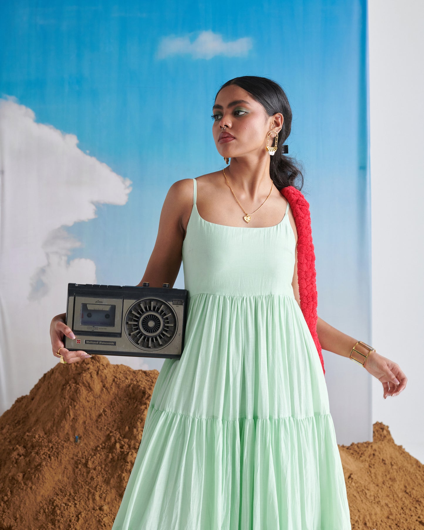 Woman in Minty Mehfil green maxi dress holding a vintage radio in front of her.