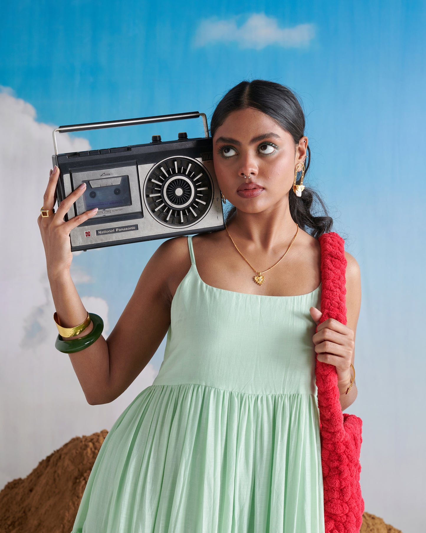 Woman in Minty Mehfil green maxi dress holding a vintage radio on her shoulder.
