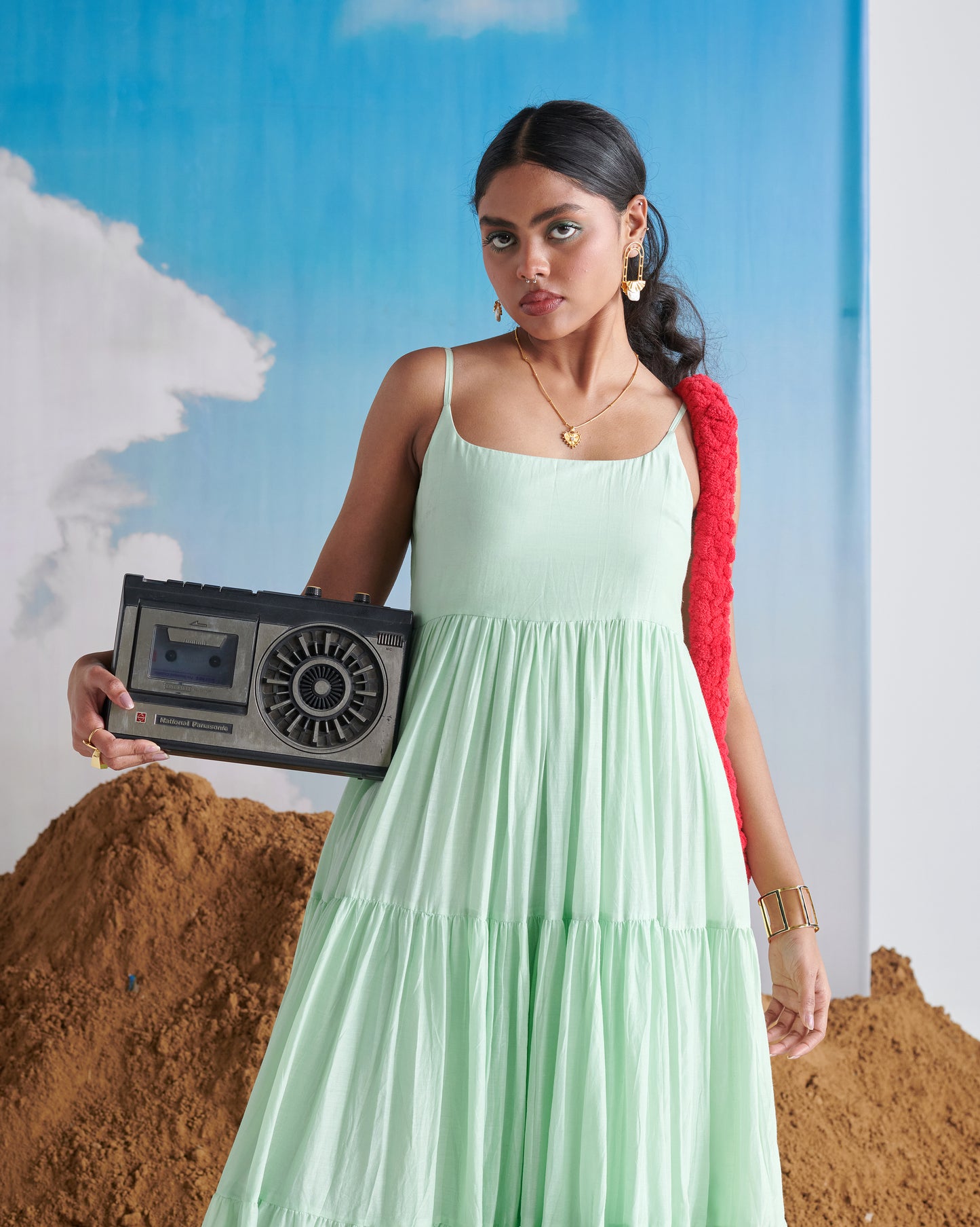 Woman in Minty Mehfil green maxi dress holding a vintage radio with red scarf.