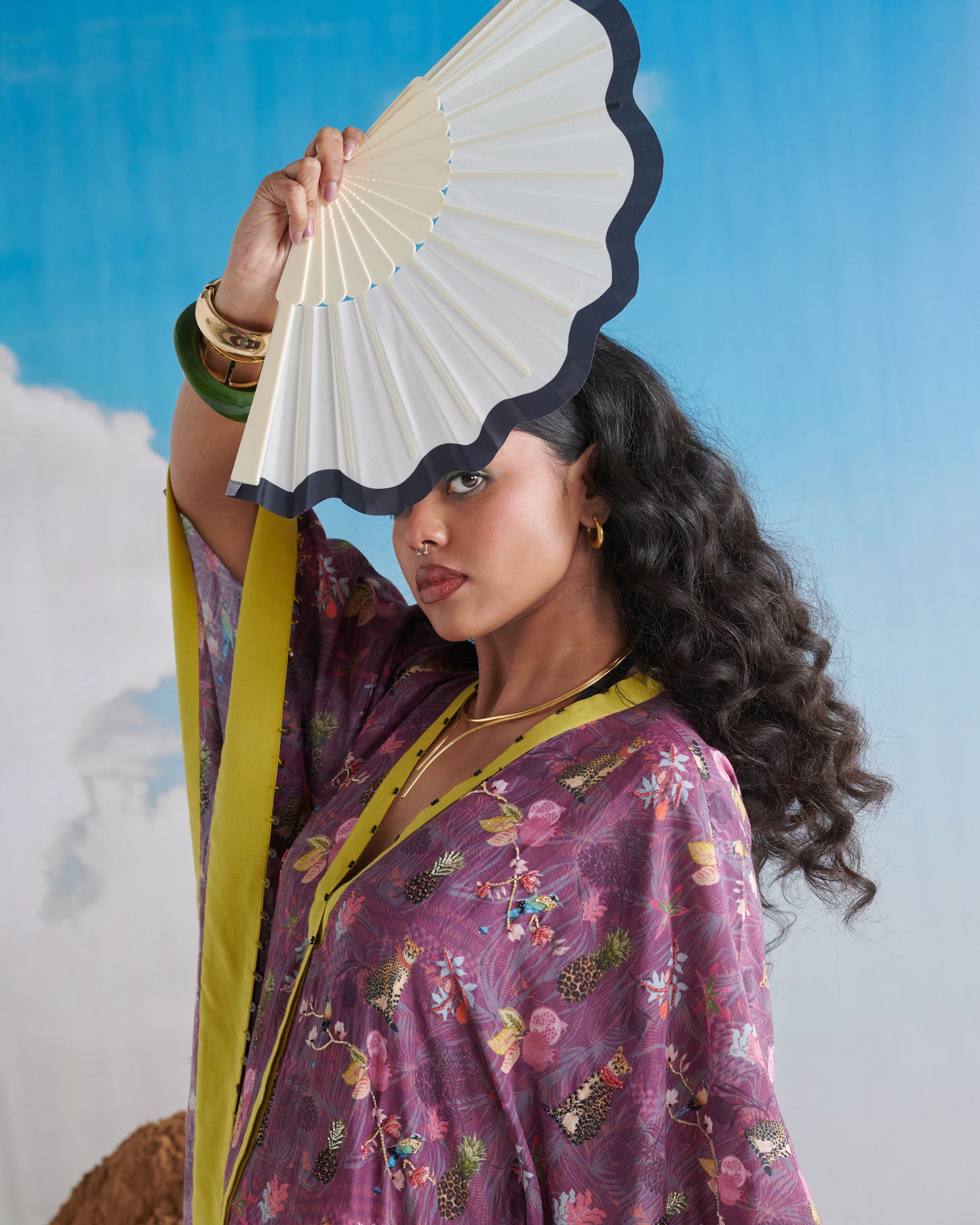 Portrait close-up with fan; Plum Passion kaftaan showing lime neckline and print.