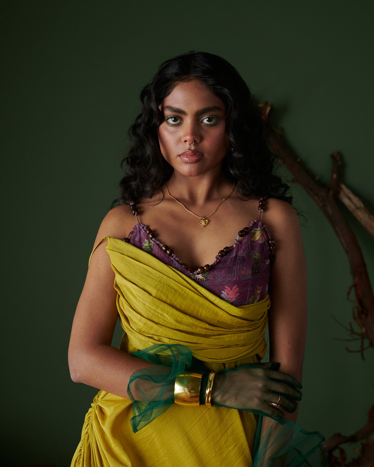 Closeup of model in Naarangi Sunheri Zest yellow dress with purple floral bodice, green mesh gloves and golden jewelry.