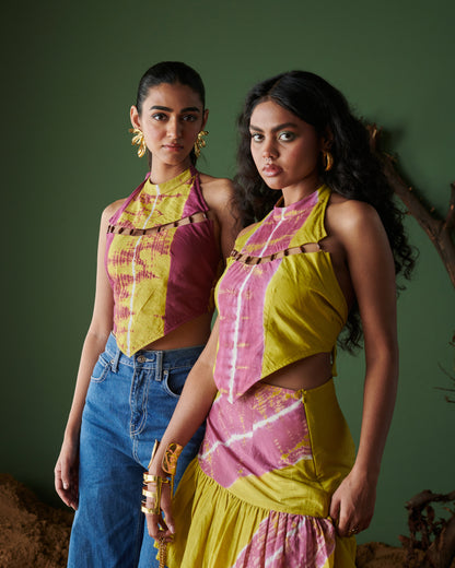 Two models wearing Khatta Jaljeera handcrafted halter-neck tops in mustard yellow and magenta pink tie-dye, one styled with a matching skirt and the other with blue denim, from Naarangi’s Chaska collection.