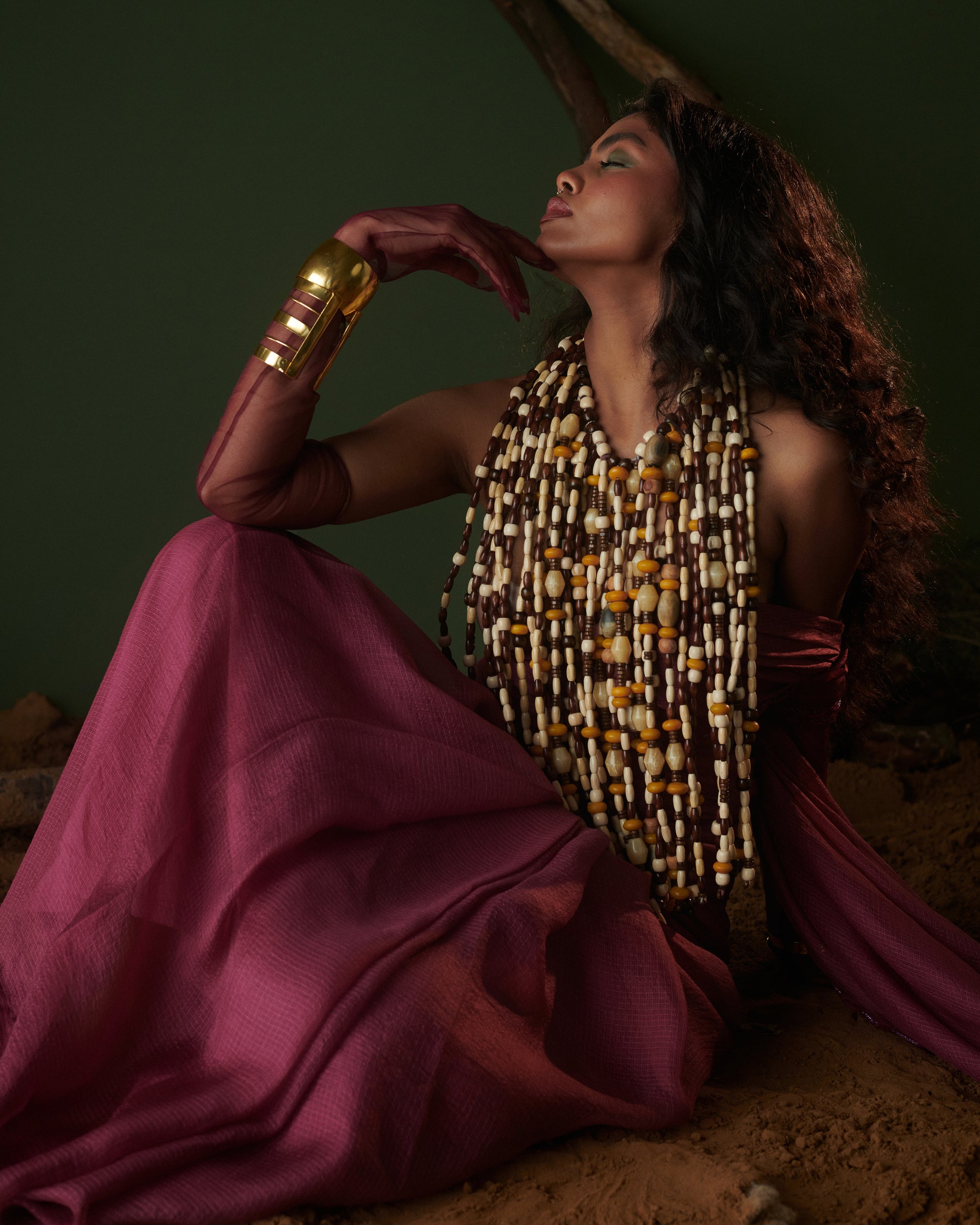 Sitting pose of model in Kokum Crush plum saree with blouse by Naarangi, airy fabric styled with bold layered jewelry.