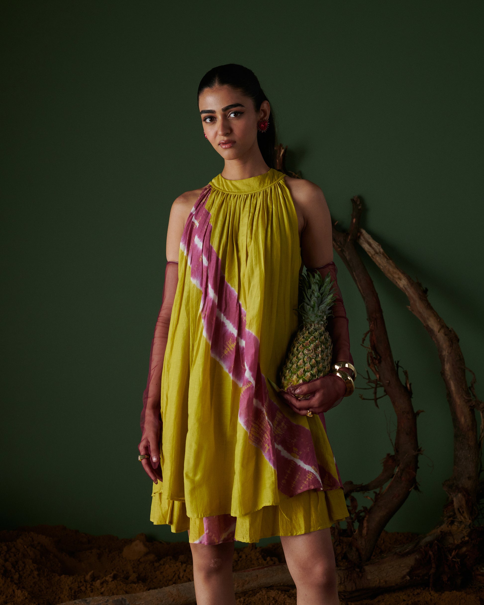 Model holding pineapple while wearing Naarangi Nimbu Twist yellow and pink dress.