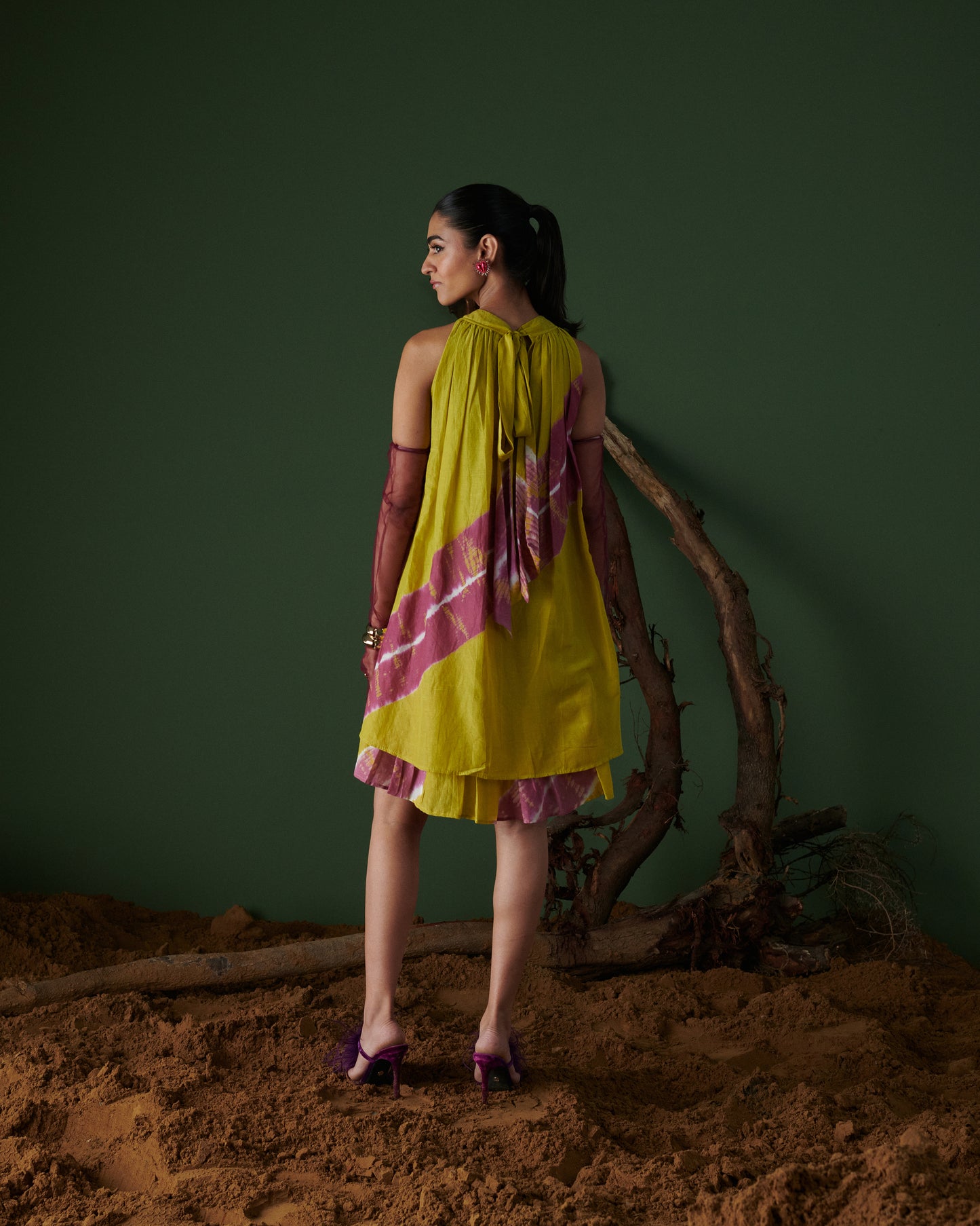 Model showcasing Naarangi Nimbu Twist yellow dress with pink tie-dye detail, back view.