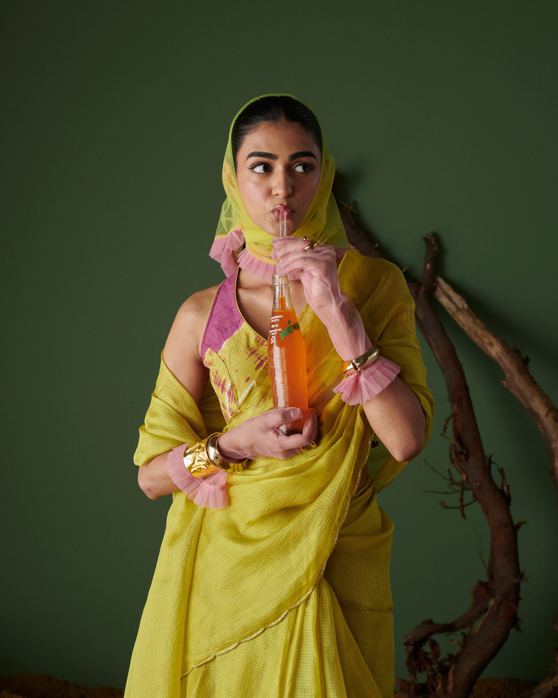 Model sipping soda in playful candid pose wearing Nimbu Soda Pop saree with blouse by Naarangi, lime yellow and magenta ethnic wear, festive traditional outfit India.