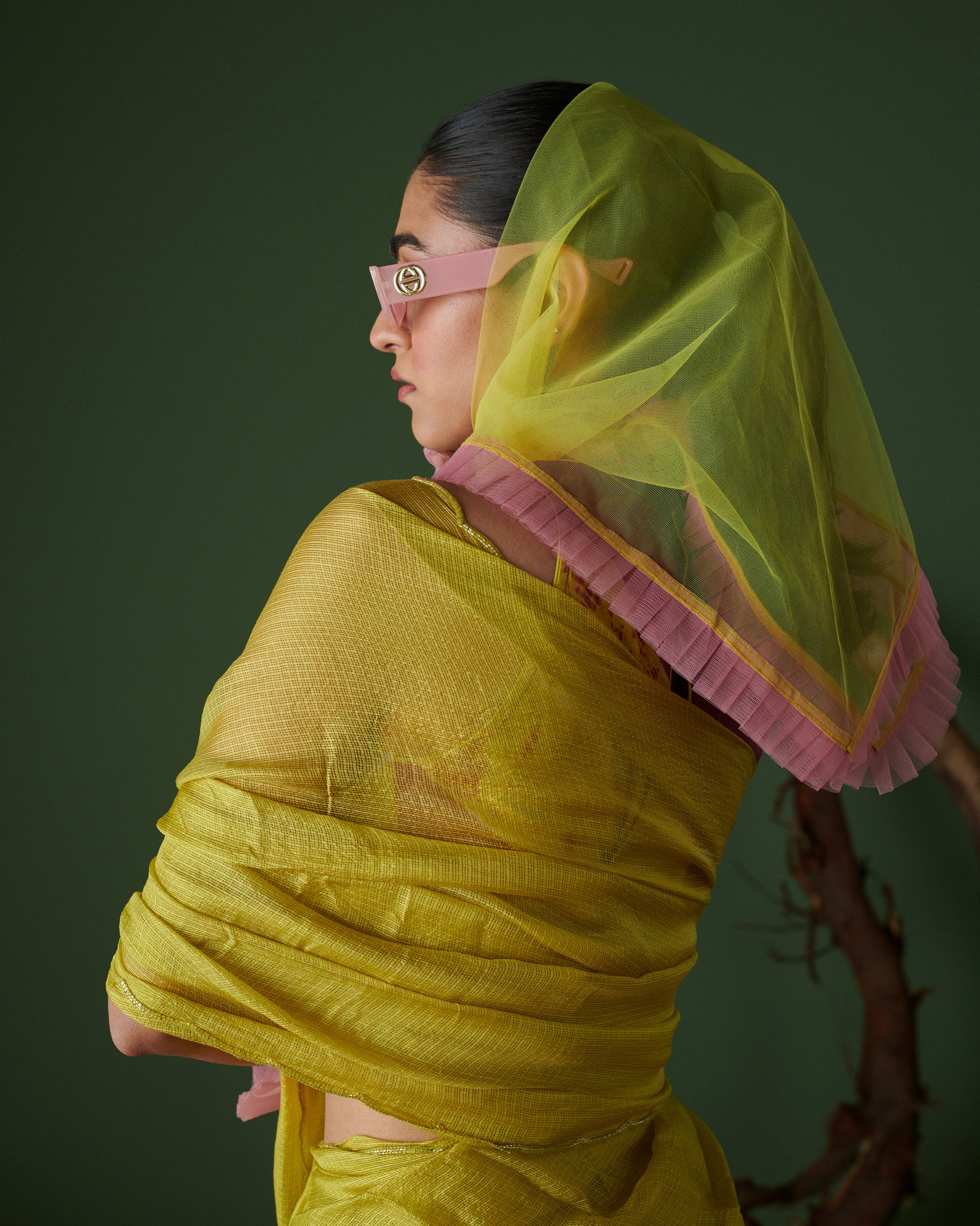Side profile of model in Nimbu Soda Pop saree with blouse by Naarangi, lime yellow saree styled with magenta blouse and pink sunglasses, elegant ethnic fashion look.