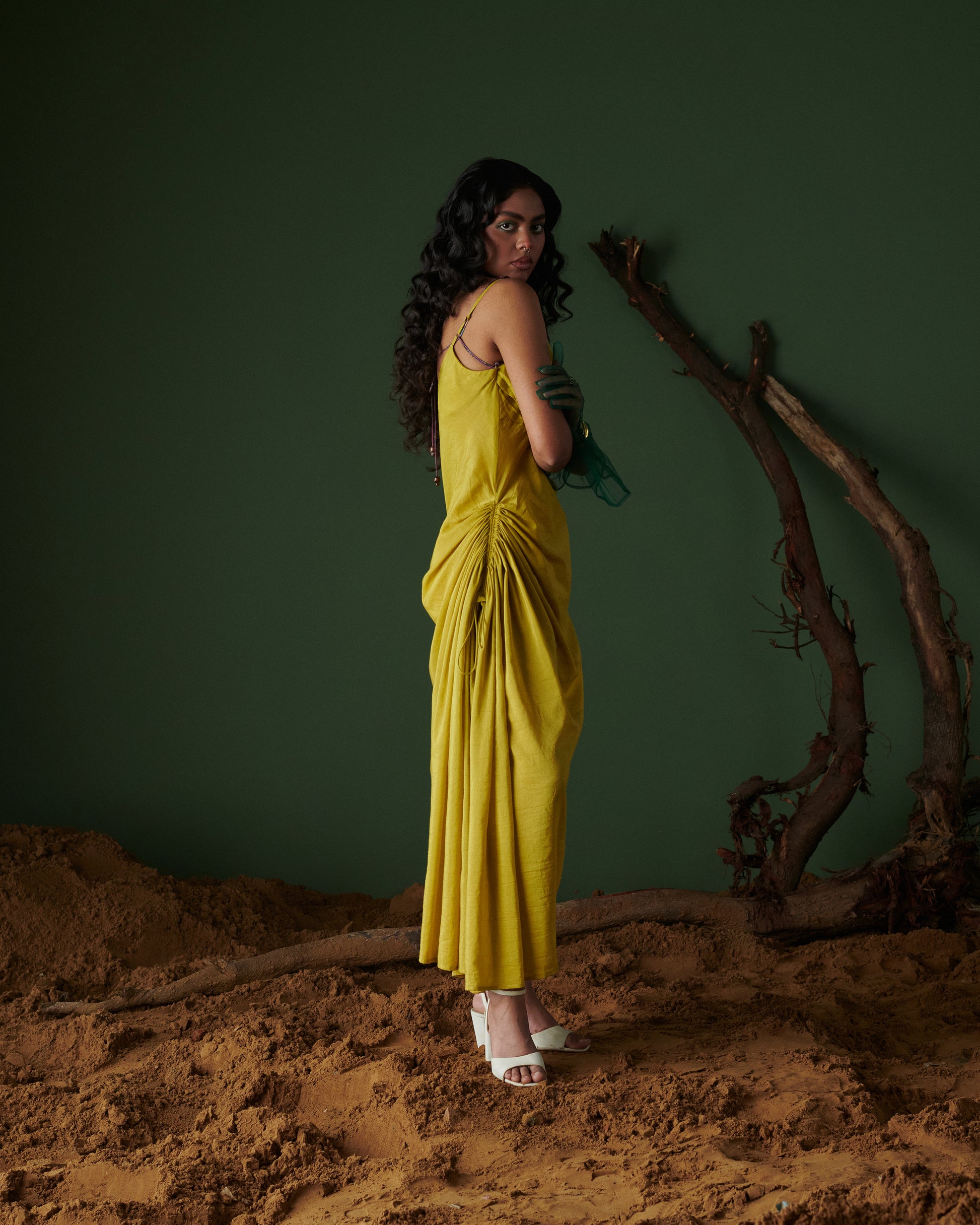 Model in Sunheri Zest Dress, yellow with ruched side drape and back tie-up, styled with white heels by Naarangi.