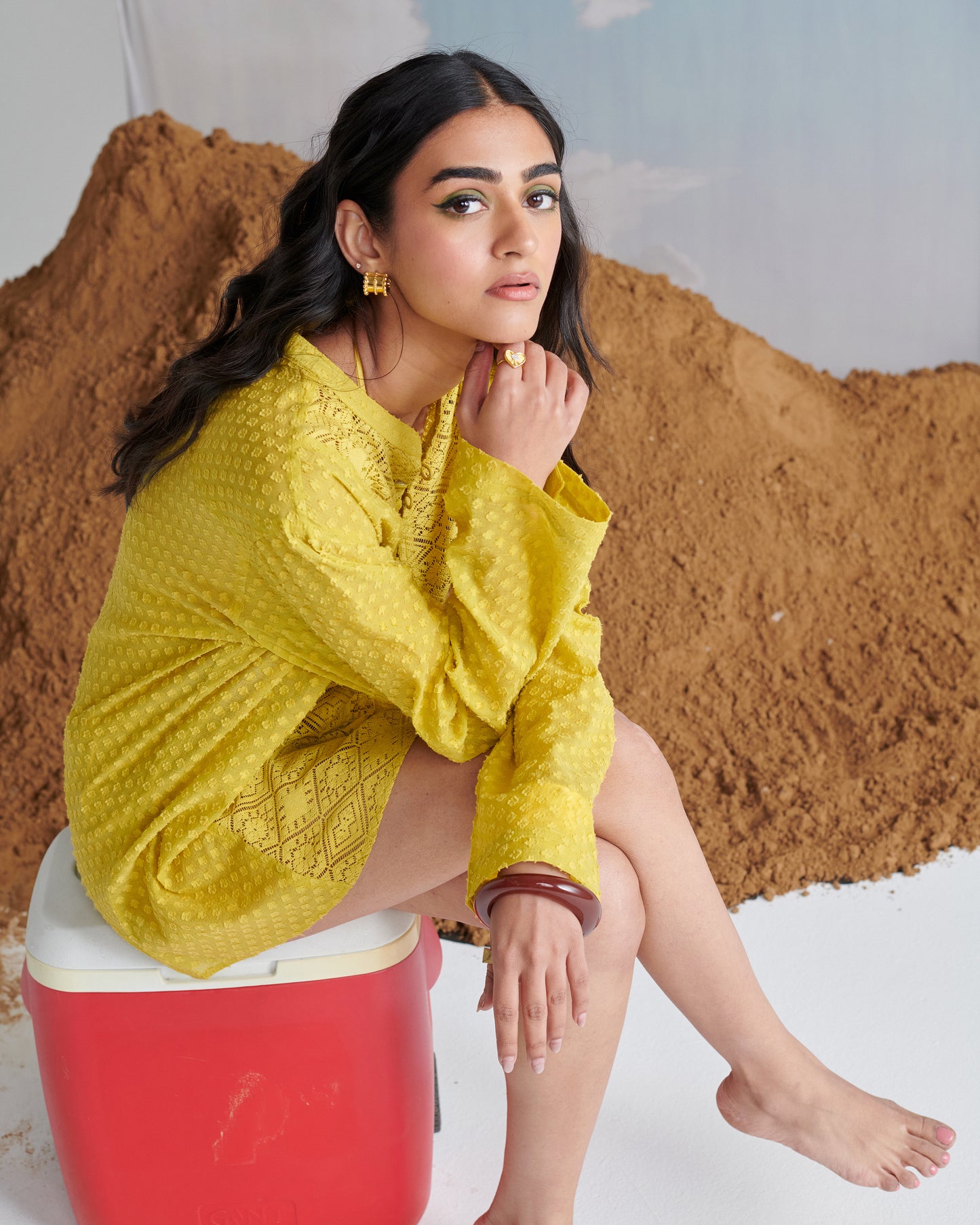 Model seated in Tangy Tadka Kurta, vibrant yellow with textured weave, long sleeves and button neckline, exuding chic casual style.